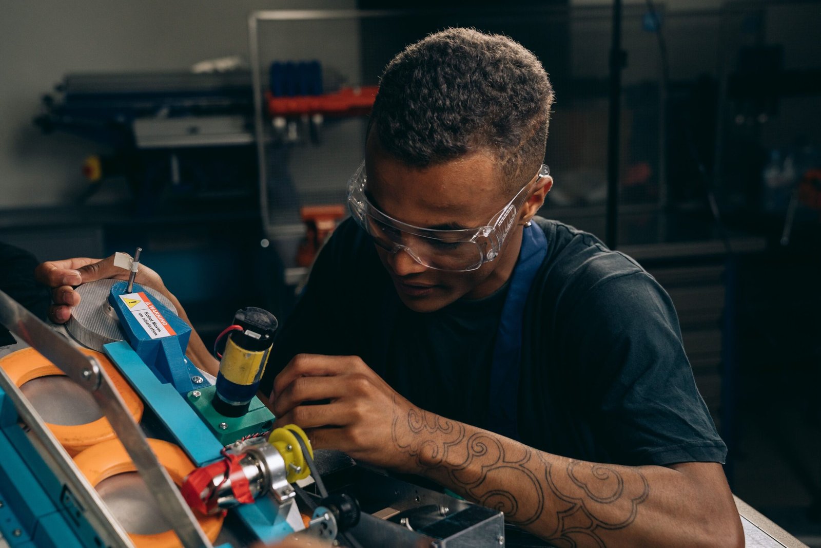 A focused engineer in safety glasses inspecting a component on a factory production line