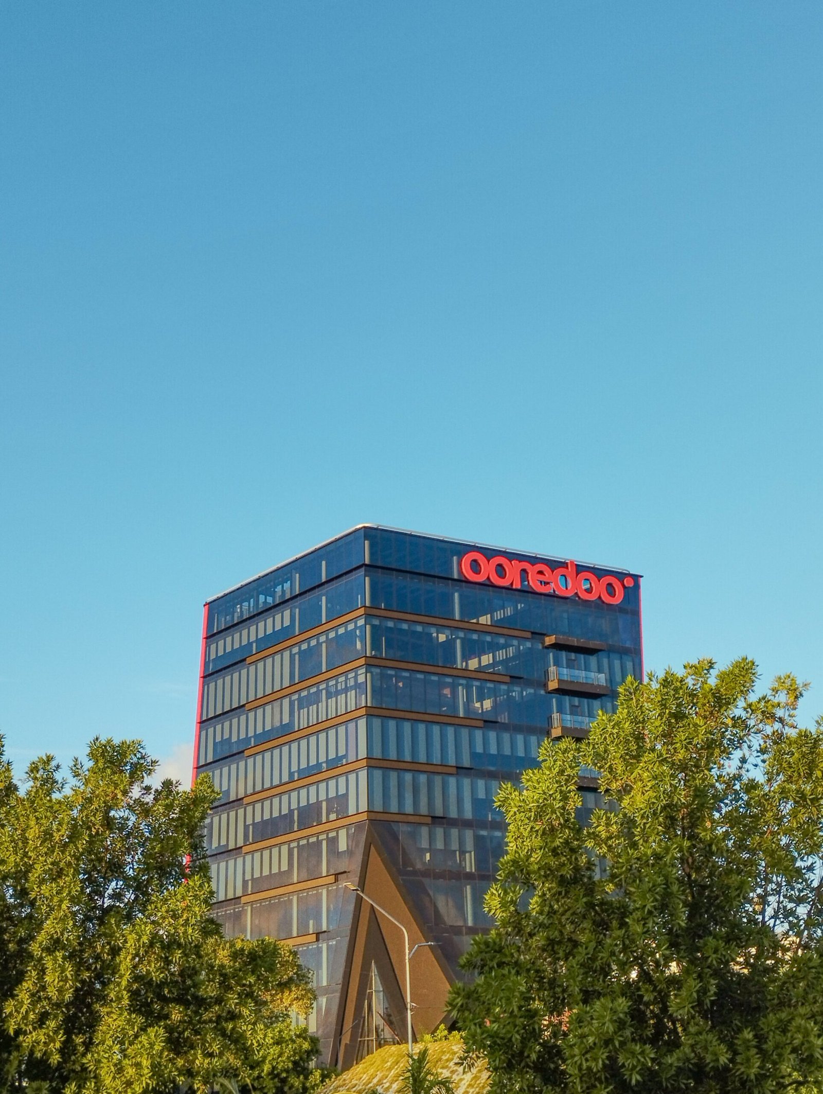 A modern glass-facade office building against a clear blue sky