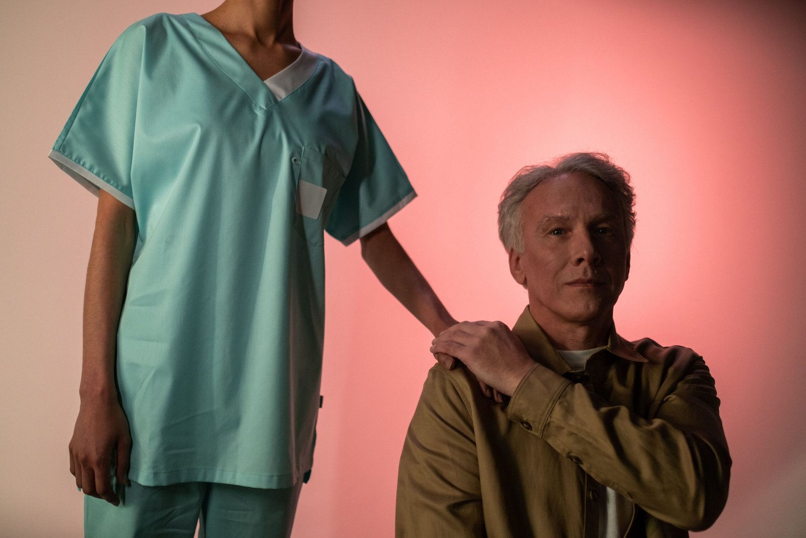 A caregiver in medical attire holding the hand of an elderly patient