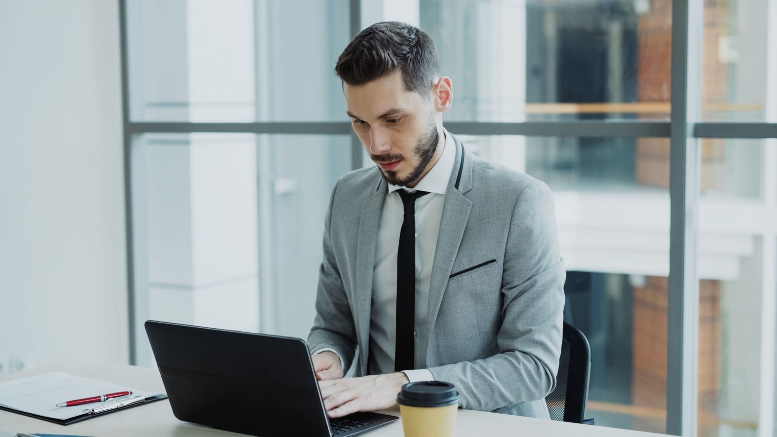 A businessman working on a laptop in a modern office, representing the kind of everyday task an AI-use example might describe