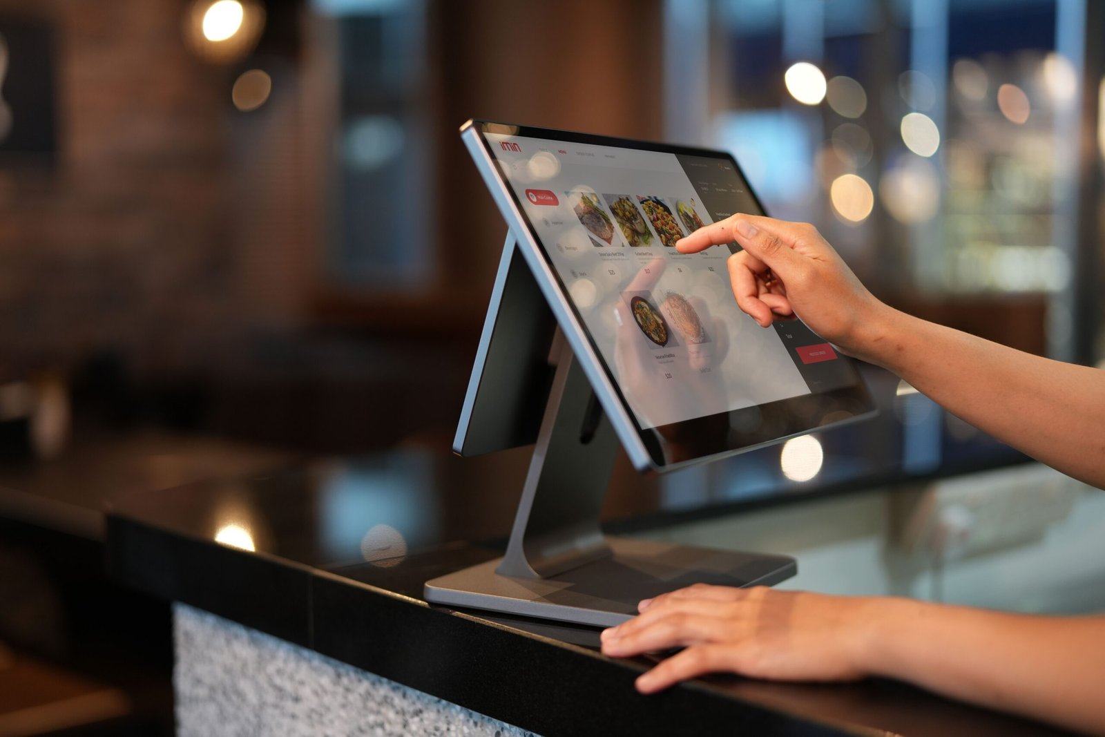 Close-up of a hand using a touchscreen point-of-sale system at a counter