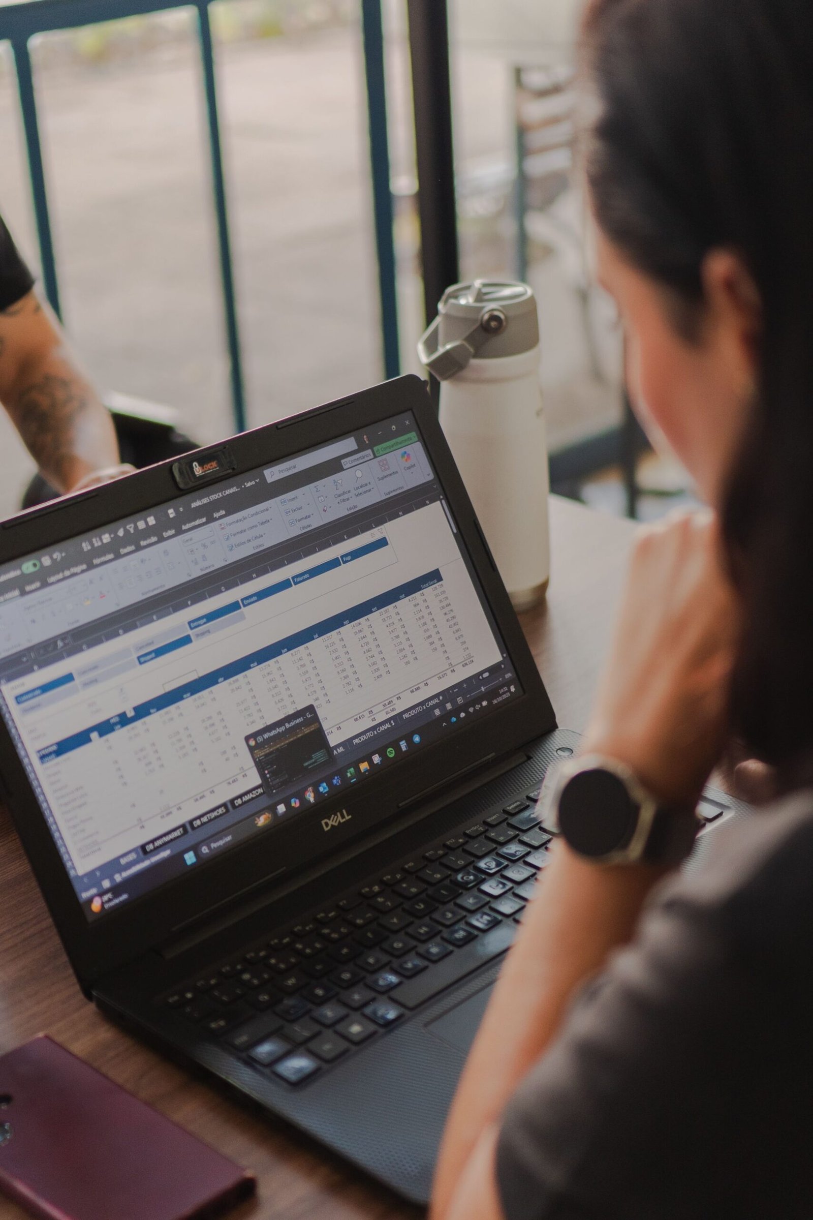 A person analyzing data on a laptop with a spreadsheet open