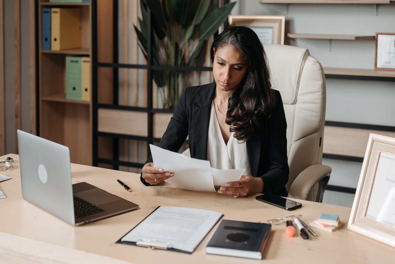 A businesswoman reviewing a stack of paperwork at an office desk