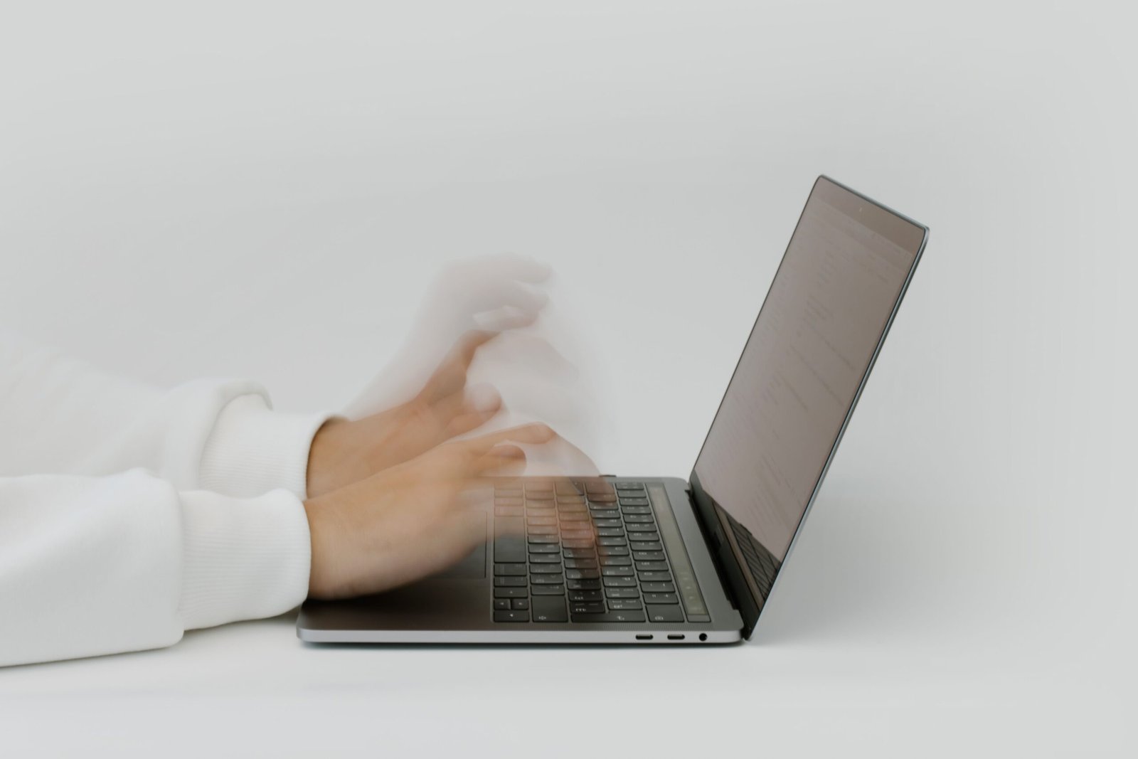 A person's hands typing on a laptop keyboard with a resume document open on the screen, focused close-up on the keys and screen edge